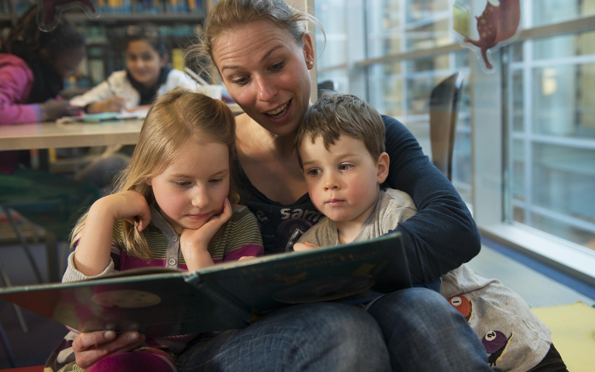 Symbolbild: Vorlesen - Mutter liest zwei Kindern vor