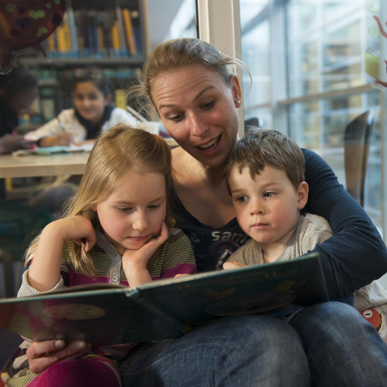 Symbolbild: Vorlesen - Mutter liest zwei Kindern vor